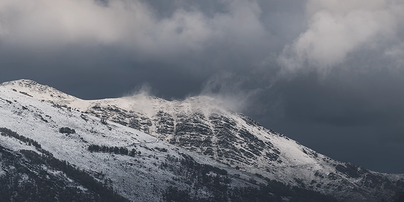 Montañas nevadas con nubes oscuras